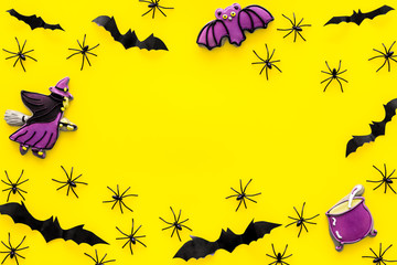 Cute Halloween decoration. Bats, spiders and special cookies on yellow background top view space for text