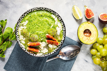 Green smoothie bowl on stone or concrete background.
