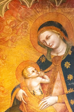 Religious medieval fresco showing Virgin Mary, in a yellow background, breast feeding baby Jesus