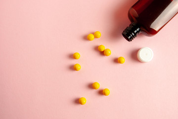 yellow pills in bottle on a pink background. flat lay.