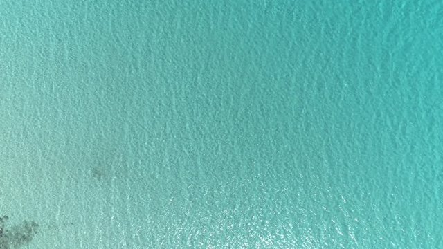 Aerial top down view. Calm clear blue sea water background. 4K