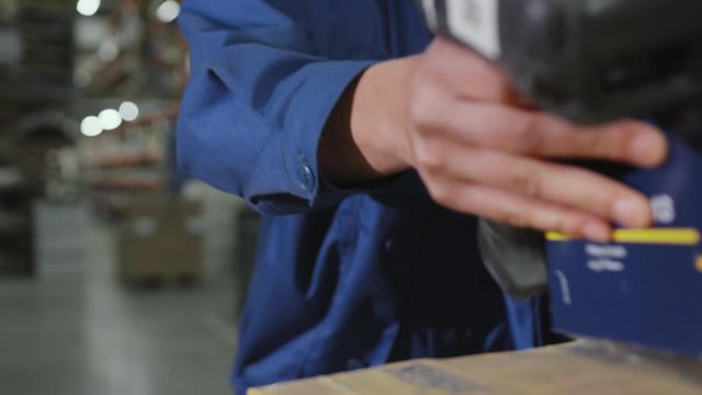 Man hands worker hold scanner for products red light cardboard commercial distribution factory logistics pack transportation warehouse indoors occupation process slow motion