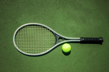 single big tennis racket on a green court with a tennis ball from above