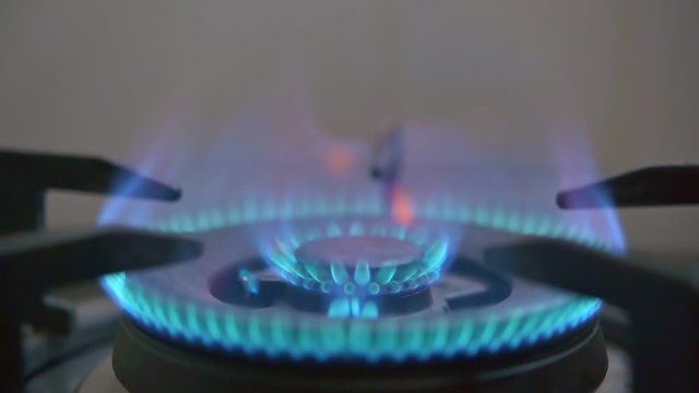 Close up slow motion footage of ignition of blue gas stove flame in kitchen.