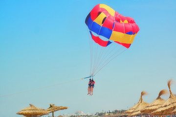Two women parasailing fly over the beach