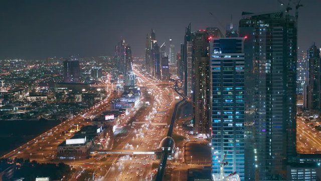 Evening skyline with modern skyscrapers and traffic on sheikh zayed road at night in Dubai, UAE. Aerial view of illuminated business bay's architecture.
