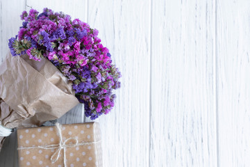 Bouquet of dried wildflowers with gift box on a wooden background. Greeting card design with flowers.