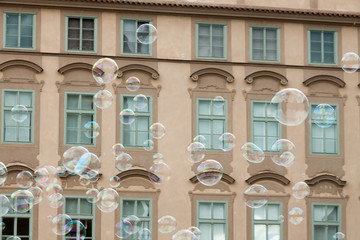 lots of transparent colorful soap bubbles brown facade building background European house