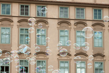 Obraz premium lots of transparent colorful soap bubbles brown facade building background European house