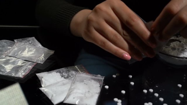 White drug powder packaged in plastic bags. Women is hands in the frame