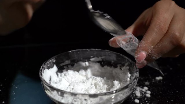 White drug powder packaged in plastic bags. Women is hands in the frame