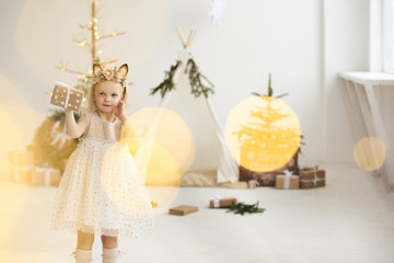 A portrait of a little girl near the wigwam and Christmas tree unpacking Christmas gifts on a white background © jul14ka