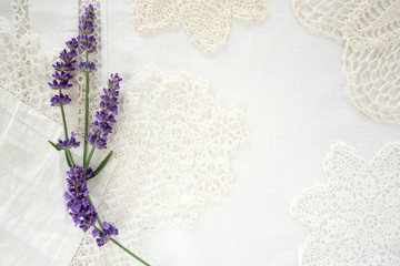 Pretty lavender flowers on linen and doilies layered background with room for copy space - obrazy, fototapety, plakaty