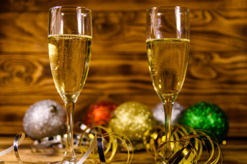 Two wineglasses with champagne and different christmas decorations on wooden table