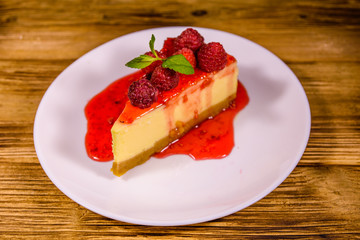 White plate with cheesecake New York, leaf of mint and raspberries on wooden table