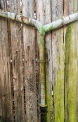 Marodes Wasserrohr an alter Bretterwand