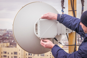 A man performs maintenance and repair of a powerful radio relay base station of mobile...