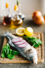 Fresh raw fish and food ingredients on table. Raw fish with spices on wooden cutting board. Top view