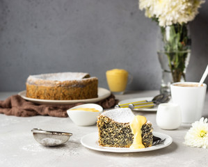 Piece of poppy seed cake with powdered sugar, custard and a cup of coffee. Traditional Polish poppy seed cake – Makovnik. Delicious breakfast or dessert. 