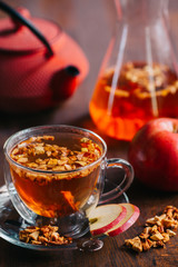 Winter berry tea with cranberries, apple, cinnamon, black mulberry, lemon, honey and thyme in a glass cup on wooden table. Horizontal, closeup view