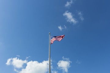 Beautiful view of American flag on green trees and blue sky with white clouds background