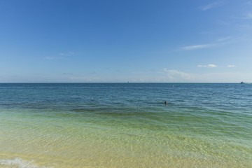 Beautiful view of Atlantic ocean.  Blue water surface merging with light blue sky in horizon line. One person is swimming. Key West, Florida. USA 