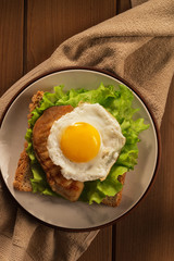 Fried egg and chicken on bread for breakfast on plate and rustic table..