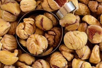 Close-up and background of many dried chestnuts as preserved dried fruits for eating with a dosing vessel for scooping in the market