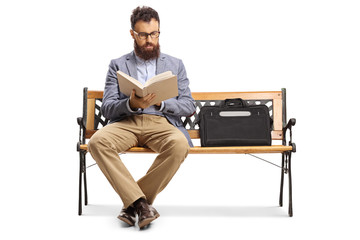 Bearded man reading a book on a bench