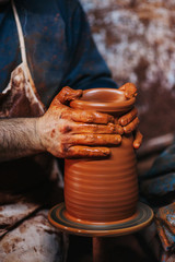 Hands of making clay pot on the pottery wheel ,select focus, close-up.