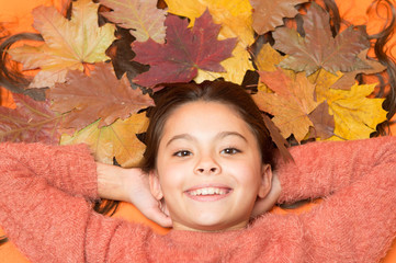 With smile on her lips. Happy smile of beauty model. Small child with cute smile. Little girl in autumn mood. Kid smiling with colorful leaves in long hair. Fall season starts with beautiful smile