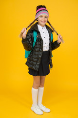 Fashion concept. Warm clothing. Buy clothes for school season. Schoolgirl fashion outfit. Fall autumn winter. Child with backpack. Fashion shop. Girl wear knitted hat and jacket yellow background