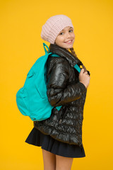 Schoolgirl fashion outfit. Child with backpack. Fashion shop. Fashion concept. Girl wear knitted hat and jacket yellow background. Adorable pupil. Fall autumn winter. Buy clothes for school season