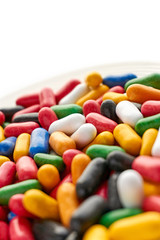 Closeup of colorful hard shiny sweet candy in blue, red, yellow, green, black an white colors on saucer. Dutch angle and isolated on top for copy space. Vertical image. 