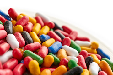 Closeup of colorful hard shiny sweet candy in blue, red, yellow, green, black an white colors on saucer. Dutch angle and isolated on top for copy space.  
