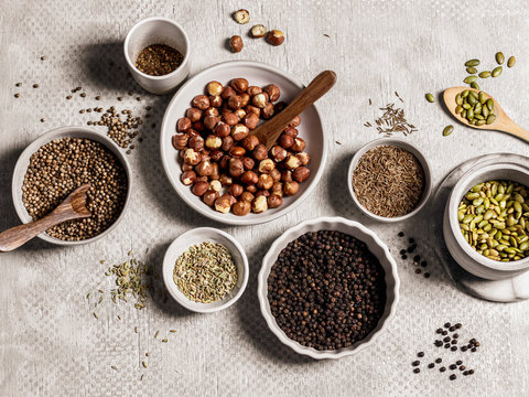 Assortment of spices, seeds and nuts in bowls on gray background