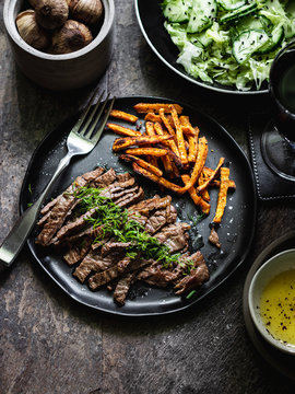 Black garlic seasoned skirt stake with sweet potato and iceberg cucumber salad in a bowl