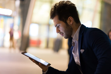 Young manager using a digital tablet outdoor in a modern city at night