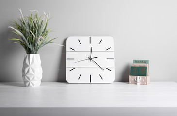 Interior. Office interior. Classic alarm clock and green grass in pot on gray background. Details of business interior.