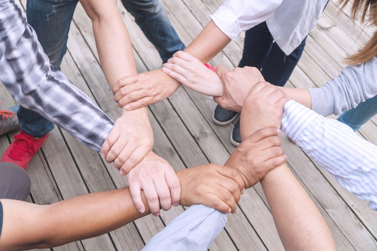 Teamwork connection success concept. Group of people holding hands circle together in the park. Human hands agreement join team partnership symbol unity.