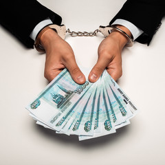 cropped view of businessman in handcuffs holding russian money on white