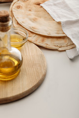 lavash bread covered with towel near cutting board with oil on white surface