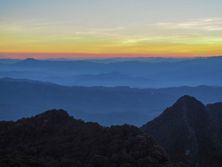Beautifully graded twilight at Chiang Dao Mountain, the horizon line is orange. Many mountains are dark blue and light.