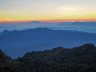 Beautifully graded twilight at Chiang Dao Mountain, the horizon line is orange. Many mountains are dark blue and light.