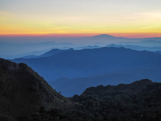 Fototapeta na wymiar Beautifully graded twilight at Chiang Dao Mountain, the horizon line is orange. Many mountains are dark blue and light.