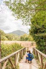 A woman and a child hiking, walking on a wooden walkway.