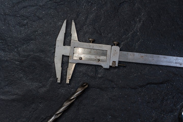 Measuring tool. Vernier caliper on black stone. Background, texture. Close-up