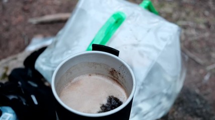 Hiker boils water for instant coffee on a small gas stove. Rack focus.