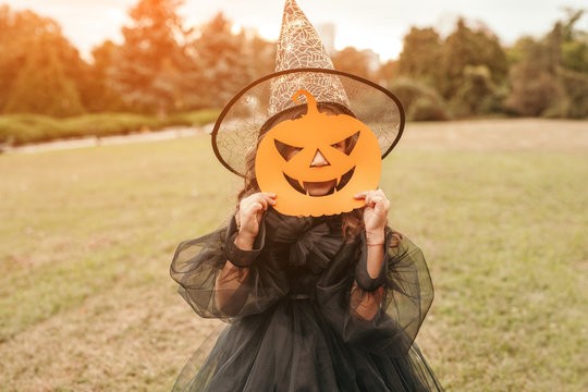 Little girl with Halloween pumpkin mask standing in field