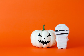 White ghost pumpkin with mummy on orange background with copy space ,  halloween concept.
